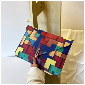 Detail of color-block envelope clutch featuring geometric patterns and golden metal lock