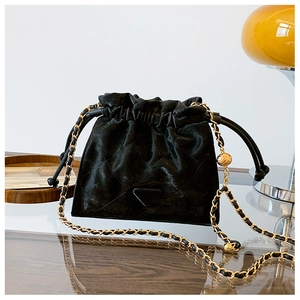 Détail d'un sac seau matelassé noir avec chaîne dorée et ornements métalliques