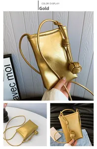 Detailed view of golden metallic phone bag featuring crinkled leather and ball knot strap