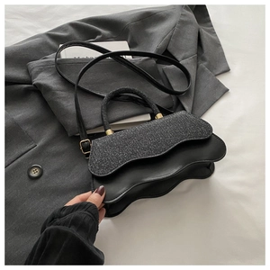 Détail du sac à bandoulière noir avec bords ondulés et finition pailletée