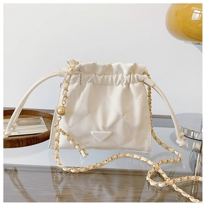 Détail du sac seau crème avec bandoulière chaîne dorée et boucle de serrage sphérique