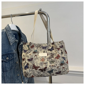 Detail of floral butterfly jacquard fabric and leather brand tag on shoulder bag