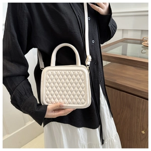 Detailed view of white quilted crossbody bag with adjustable strap on model