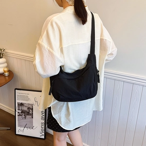 Minimalist black nylon crescent crossbody bag with stylish woven zipper pulls and wide strap