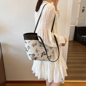 Fashionable butterfly print tote bag with black leather straps shown on a model