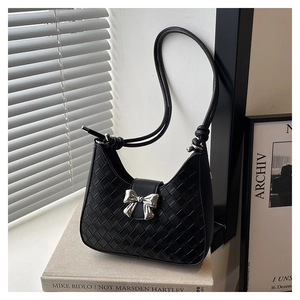 Detail of black woven shoulder bag featuring a silver metal bow buckle and knot strap