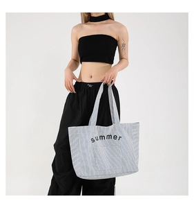 Détail du sac cabas en toile à rayures bleues et blanches avec imprimé été noir