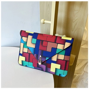 Close-up of geometric puzzle pattern envelope clutch bag with golden metal buckle
