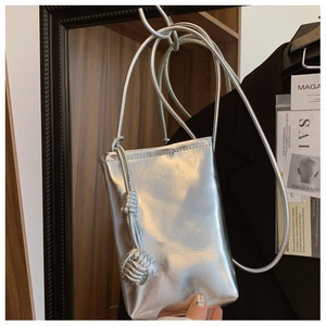 Detail of silver metallic crossbody phone bag with woven ball charm and slim strap