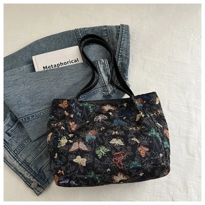 Close-up of vintage floral butterfly jacquard fabric on a black shoulder tote bag