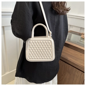 Chic white quilted crossbody bag with top handle shown on model in a minimalist interior