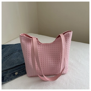 Detail of pink woven leather tote bag showing fine texture and slender shoulder strap