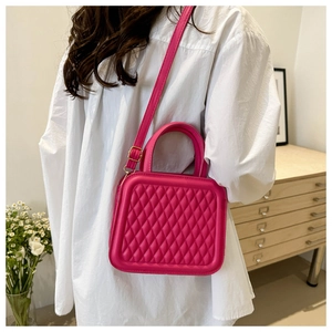 Detailed view of magenta quilted crossbody bag with golden hardware and top handle
