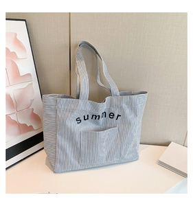 Gros plan du sac cabas en toile rayé bleu et blanc avec poche avant et motif summer