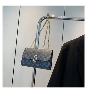 Detail of dark grey clover-patterned crossbody bag with gold chain and oval buckle