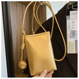 Detail of a golden textured crossbody phone bag with spherical knot and thin strap