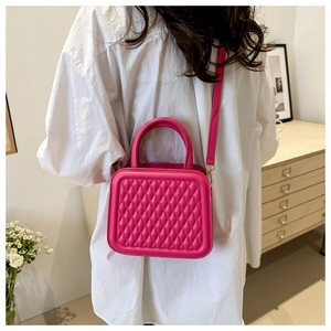 Magenta quilted crossbody bag shown on a model with white shirt in a cozy interior