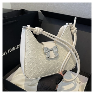 Detail of white woven handbag featuring silver bow buckle and knotted shoulder strap