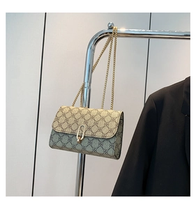 Detail of vintage clover pattern on leather crossbody bag with golden chain and U-buckle