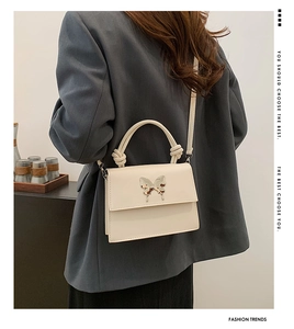 Détail du sac beige avec boucle papillon en métal et poignée à motif nœud élégant
