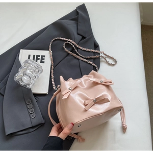Détail du sac seau rose brillant avec nœuds 3D et bandoulière en chaîne argentée