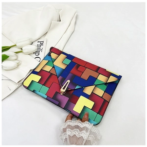 Detail of colorful geometric envelope clutch with gold metal clasp on white background