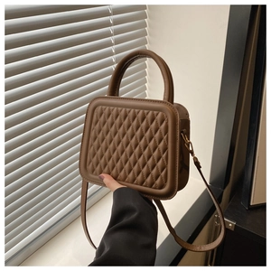 Detailed view of coffee brown quilted small square bag with metallic buckle and strap