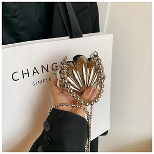 Detailed shot of a silver shell-shaped mini bag with metallic beaded handle and chain strap