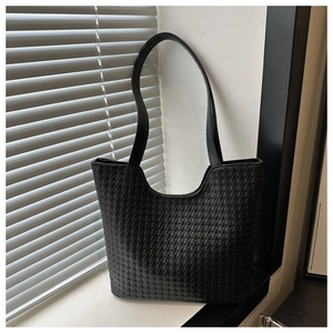 Close-up detail of the black woven texture and leather craftsmanship on the tote bag