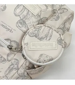 Detail of beige tote bag featuring bear print and round coin purse with zipper closure