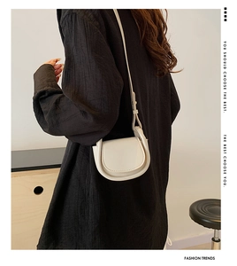 Minimalist cream saddle bag with metal ring detail shown on model back view