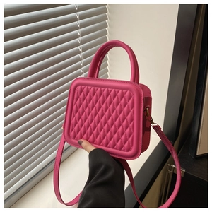 Close-up of fuchsia quilted square bag with textured diamond pattern and top handle
