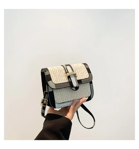 Detail of a woven straw square bag with grey plaid fabric trim and gold metal buckle
