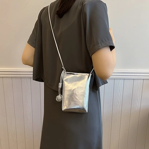 Minimalist silver metallic crossbody phone bag with knot detail shown on model