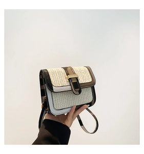 Detail of woven straw texture and gold metal buckle on a retro crossbody square bag
