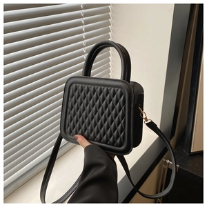 Detail of vintage quilted texture on black mini crossbody bag with golden hardware