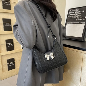 Minimalist black woven leather shoulder bag featuring a silver metal bow accent