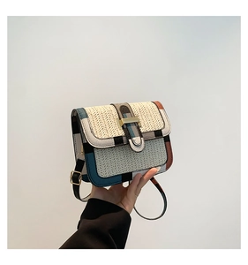 Detail of woven straw crossbody bag with multi-color leather trim and gold metal clasp
