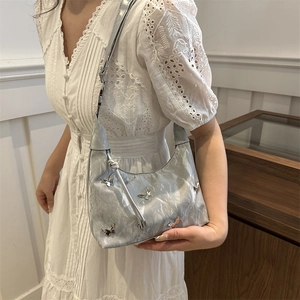 Sac hobo argenté avec breloques papillons et texture plissée sur une robe en dentelle