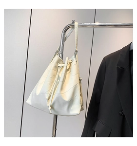 Detail of white leather bucket bag with geometric stitching and silver metal buckle