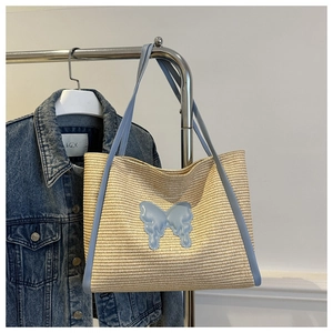 Detail of summer straw tote bag with blue leather trim and a butterfly patch