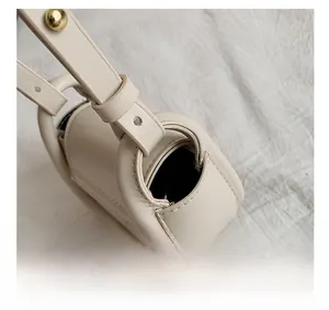 Close-up of cream leather bag handle with premium gold metal buckles and fine stitching