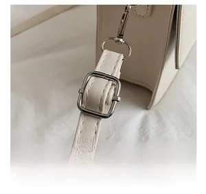 Détail de la bandoulière réglable avec boucle argentée sur un sac à main crème en similicuir