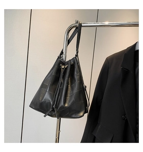 Detail of black textured bucket bag featuring patchwork pattern and drawstring closure