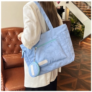 Detail of light blue nylon tote bag with bear print and functional exterior pockets