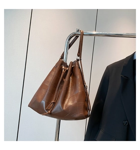 Detail of dark brown leather bucket bag with geometric patchwork and drawstring closure