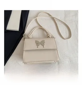 Comparaison de taille d'un sac à main crème avec boucle papillon et un téléphone portable