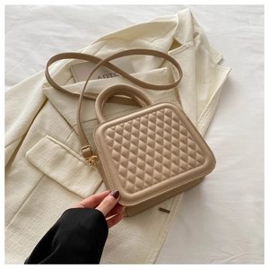 Close-up of beige quilted square crossbody bag with gold hardware and top handle