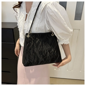 Close-up of black pleated texture tote bag with metallic ring and fashion embossing