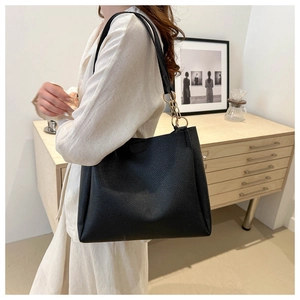 Dettaglio della borsa tote in pelle nera con catena dorata su una modella donna